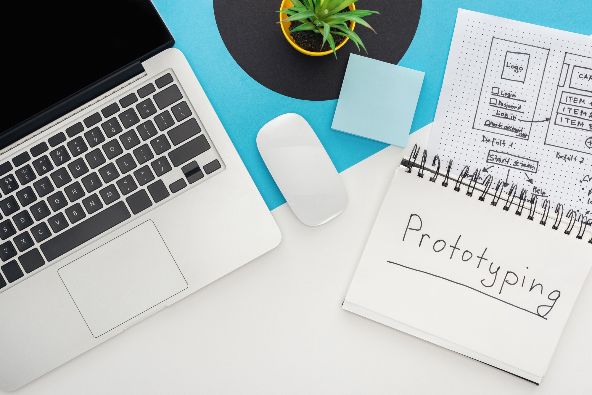 top view of laptop, computer mouse, plant, website design template, notebook with prototyping